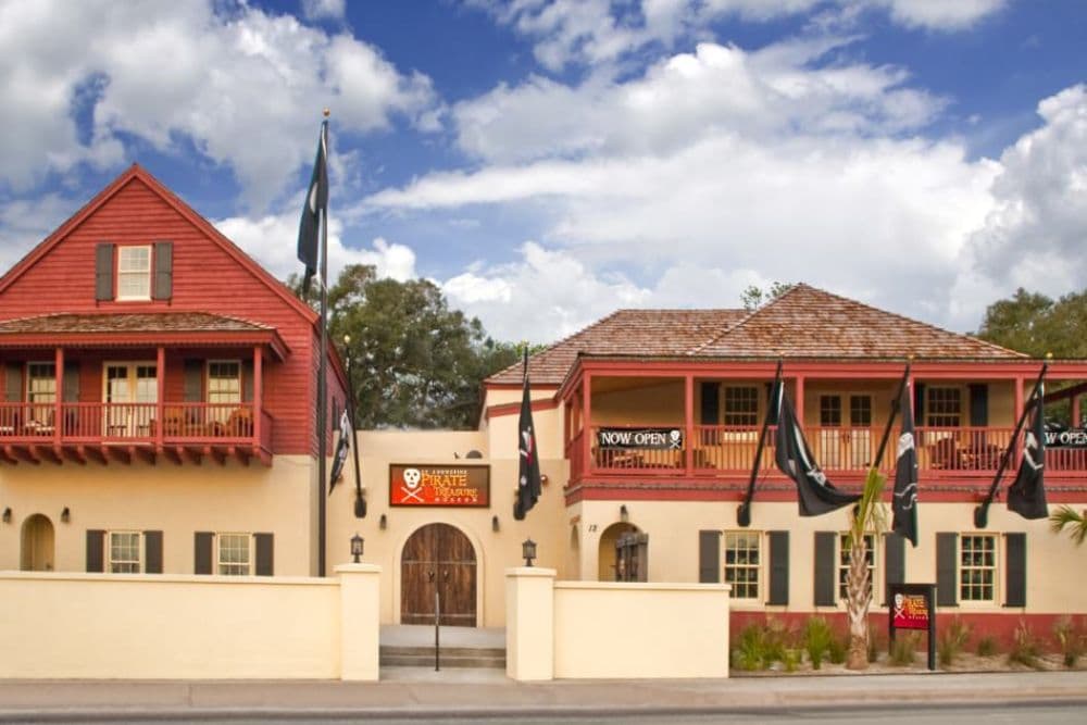 A pirate-themed building with balconies and flags, featuring a sign that reads "NOW OPEN."