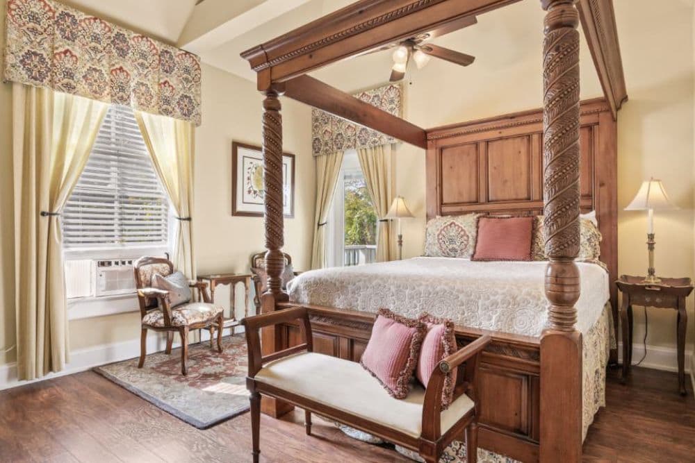 A cozy bedroom featuring a four-poster bed, elegant drapes, and a mix of classic furniture.